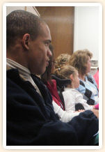 A man sitting with others, listening to a presentation