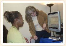 A girl using her head movement to select a message on a communication device, as another woman watches